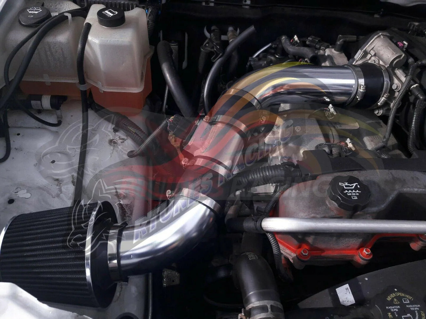 Rtunes Racing polished chrome cold air intake kit with black conical filter installed in a 3.7L engine bay.
